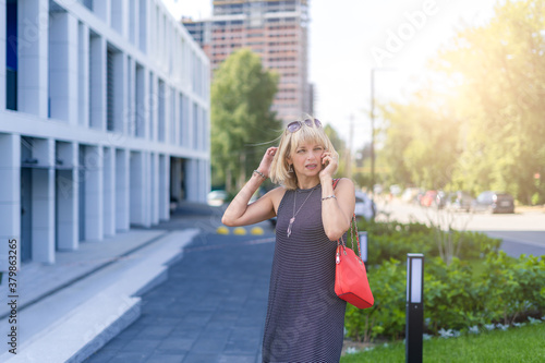 Beautiful adult woman talking on the phone outside on a urban city street. Happy lady girl with blonde hair relax outdoors
