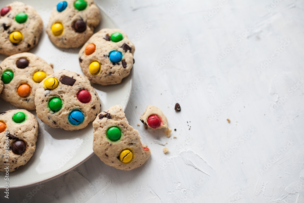 Chocolate chip american cookies and colored sweets on a plate on a gray background. For calendar, cookbook, recipes, cards. Chocolate chip american cookies and colored sweets on a plate on a gray background. For calendar, cookbook, recipes, cards.