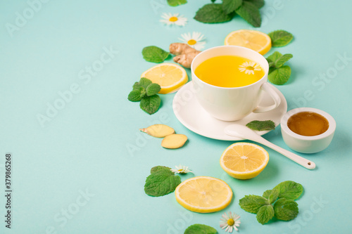 Herbal tea of chamomile flower with mint, ginger, lemon, honey on paper blue background.