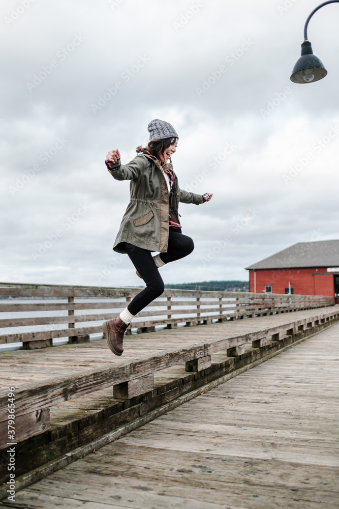Happy Asian woman jumping on a boardwalk Happy Asian woman jumping on a boardwalk