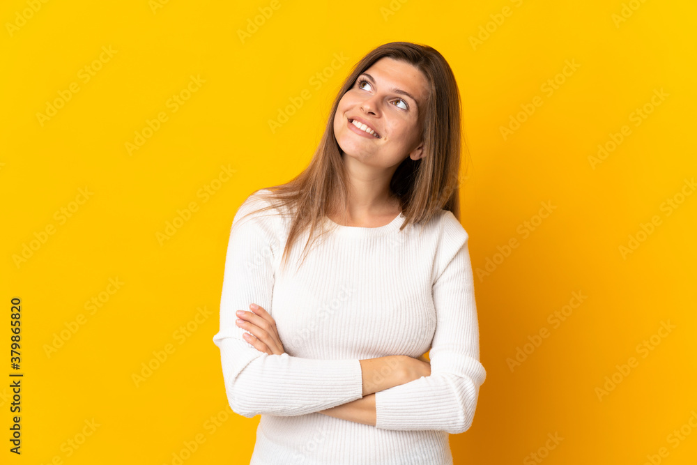 Young Slovak woman isolated on yellow background looking up while smiling Young Slovak woman isolated on yellow background looking up while smiling
