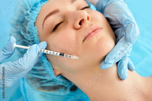 The doctor cosmetologist makes the rejuvenating facial injections procedure for tightening skin. Cosmetology concept.