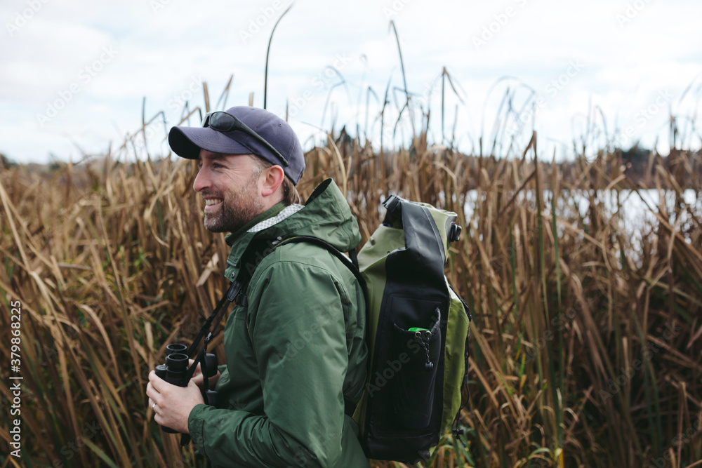 Birding man outside watching birds at a lake Birding man outside watching birds at a lake