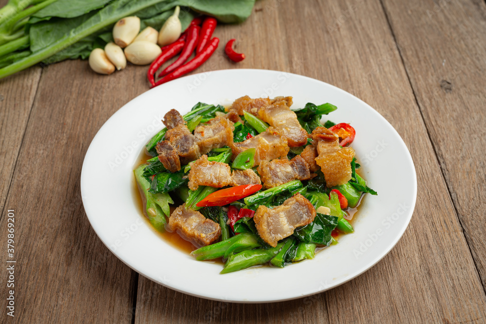 Stir fried kale, spicy crispy pork on wooden table Thai food concept. Stir fried kale, spicy crispy pork on wooden table Thai food concept.