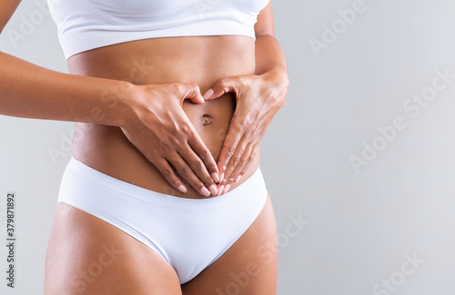 Cropped of woman making heart shape with hands over belly