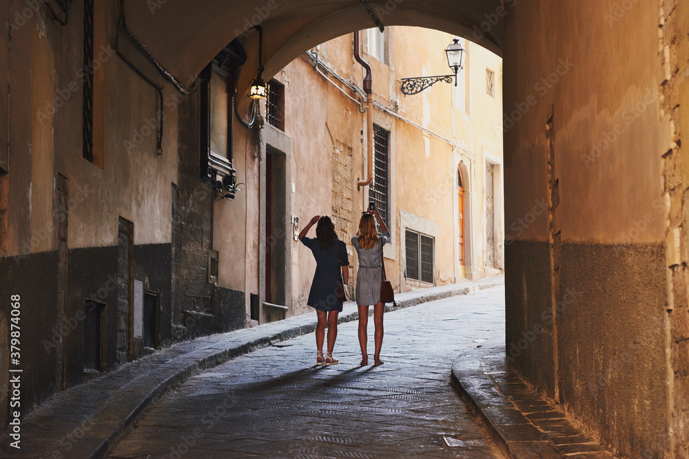 Two girl friends photograph architecture buildings with smart ph Two girl friends photograph architecture buildings with smart ph