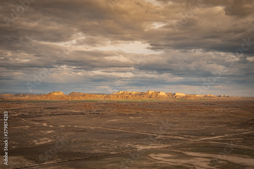 Distant view of arid mountains in the horizon with the sun appearing between the clouds in the Spanish Badlands Bardenas Reales National Park 