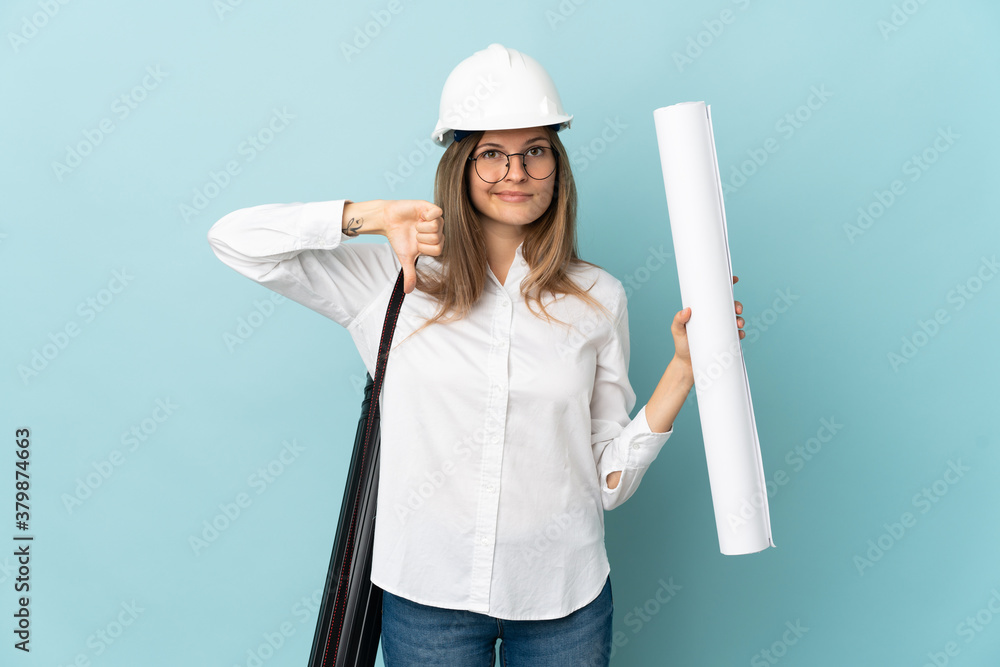 Slovak architect girl holding blueprints isolated on blue background showing thumb down with negative expression Slovak architect girl holding blueprints isolated on blue background showing thumb down with negative expression