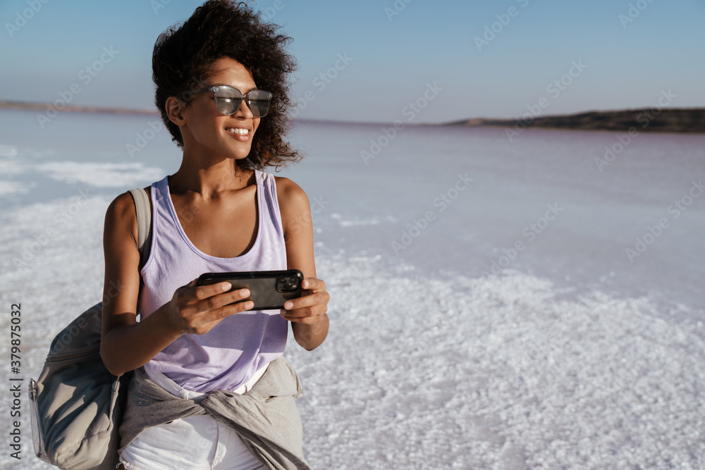 Image of happy african american woman smiling and using cellphone