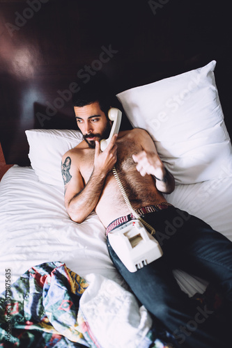 man talking on tthe phone on bed photo