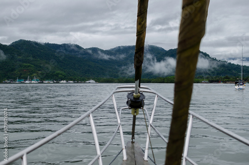 View to sea water and green hills through nose and sails of yach photo