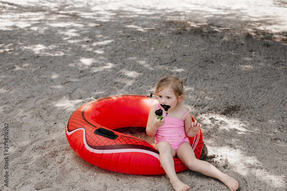 little girl eating black ice cream on the beach. Lifebuoy. Dirty child little girl eating black ice cream on the beach. Lifebuoy. Dirty child
