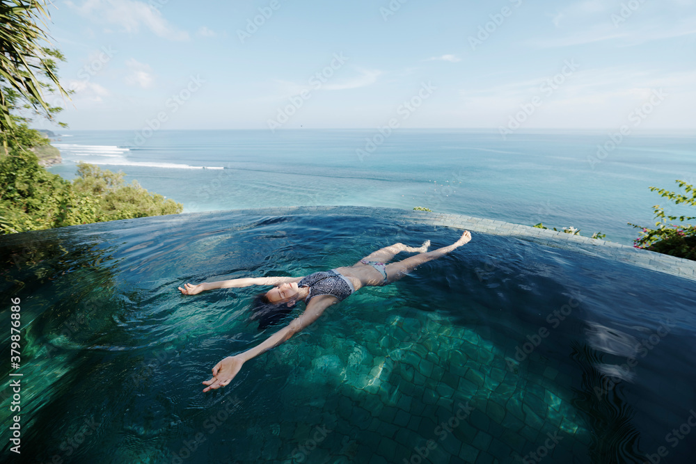 Young attractive woman floating in an infinity pool Stock Photo Adobe