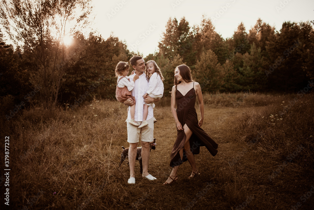 Cheerful young family with two children plays and dances in the field in summer, daughter with Down syndrome in a Caucasian family, lifestyle and brown toning. Candide childhood and parenting