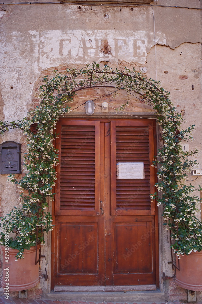 Door surrounded by flowers in Boccaccio street in the ancient medieval village of Certaldo, Tuscany, Italy