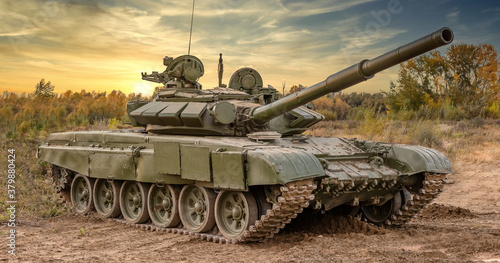 A side shot of russian tank T-64 in the field. Beautiful sunset sky as a background.
