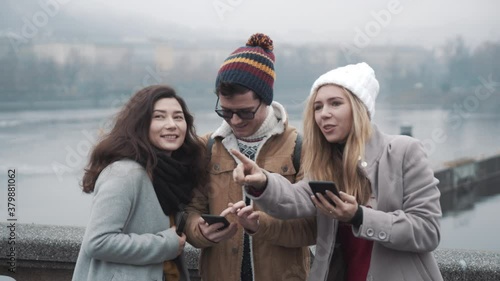 Three friends looking at mobile map and standing in Prague city. Travel, friendship, lifestyle, holiday concept. Filmed on RED camera, 10 bit clolor photo