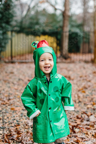 Cute young boy running around in a frog raincoast photo