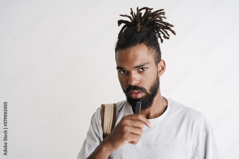 Photo of unshaven african american guy smoking electronic cigarette