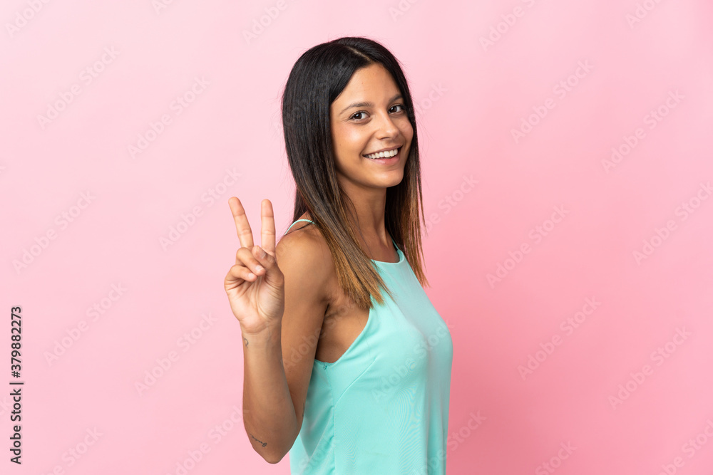 Caucasian girl isolated on pink background smiling and showing victory sign Caucasian girl isolated on pink background smiling and showing victory sign