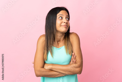 Caucasian girl isolated on pink background making doubts gesture while lifting the shoulders