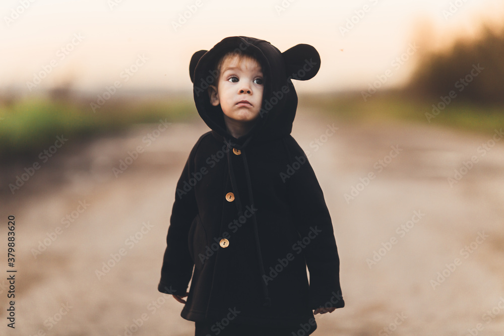 Little boy dressed in murine black coat on the rural road Little boy dressed in murine black coat on the rural road