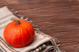 Autumn concept, little organic pumpkin and light brown plaid on wooden table. Place for text