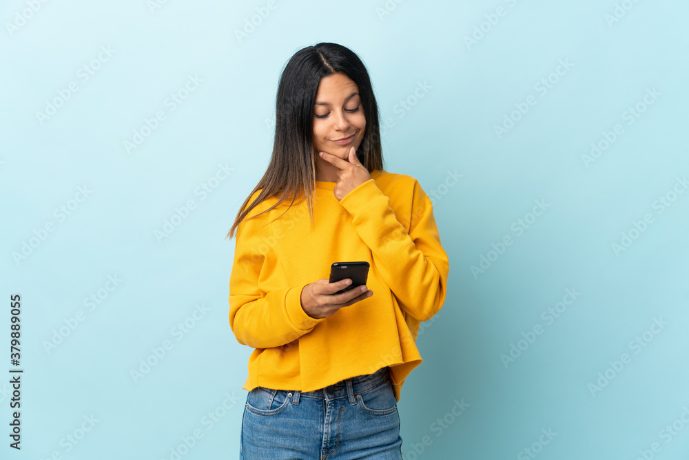 Caucasian girl isolated on blue background thinking and sending a message Caucasian girl isolated on blue background thinking and sending a message