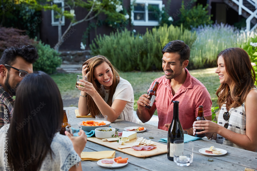 Group of young millennial friends in their backyard enjoying drinks and snacks Group of young millennial friends in their backyard enjoying drinks and snacks
