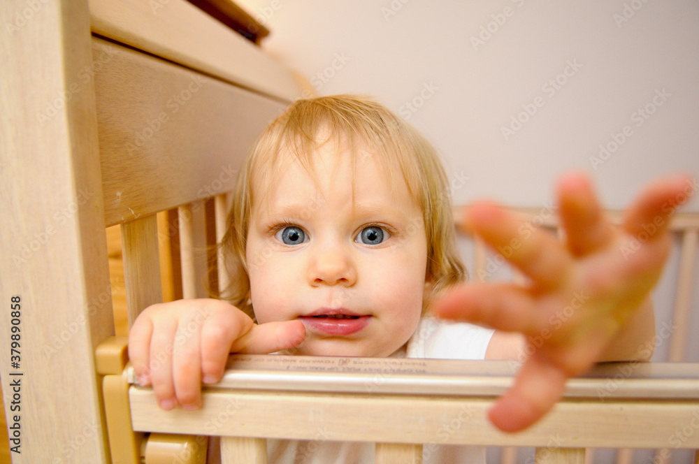 Cute Baby Girl Reaching Out While standing in Crib at Home Cute Baby Girl Reaching Out While standing in Crib at Home