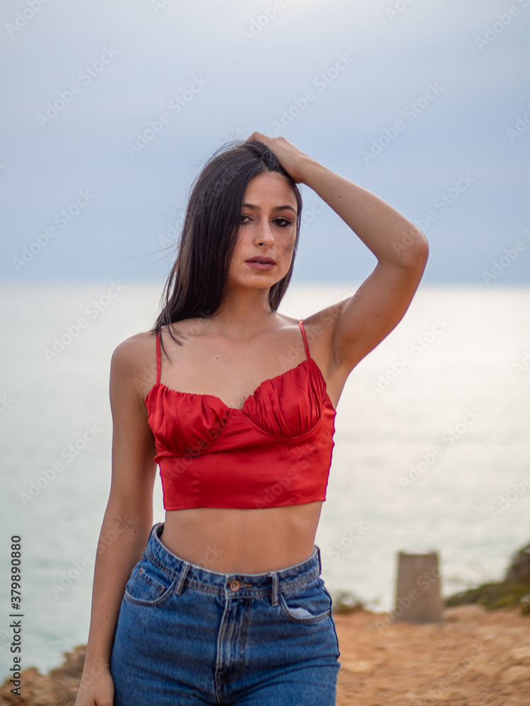 Mujer joven posando con el mar de fondo durante el atardecer Mujer joven posando con el mar de fondo durante el atardecer