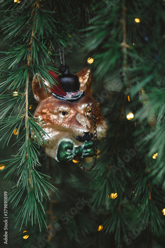 Close up of fox wearing monocle glass ornament and lights on Christmas tree photo