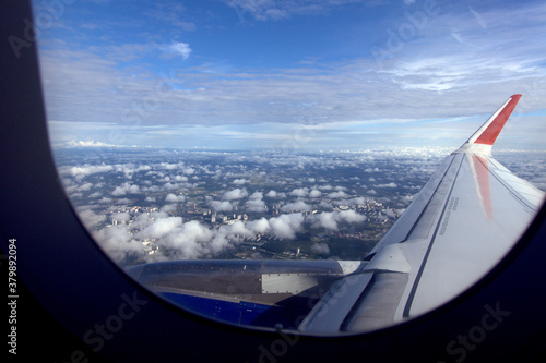 View from the airplane window. View of the wing of a flying plane and the city under the clouds.