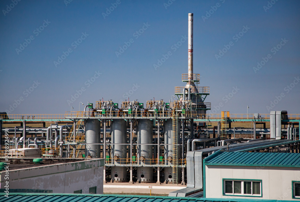 Oil refinery plant close-up. Pipelines and columns on blue sky background. Petrochemical industry.