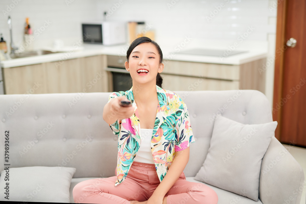 television, relax, home and happiness concept - smiling teenage girl sitting on couch with tv remote control at home television, relax, home and happiness concept - smiling teenage girl sitting on couch with tv remote control at home