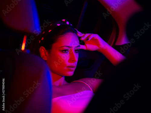 Mujer joven en un coche con luces de colores