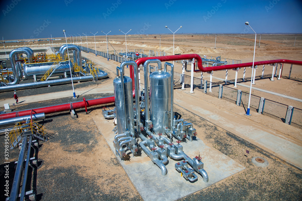 Oil refinery plant in desert sand. Panorama. Red pipes, heat exchanger, other metal equipment and red valves.