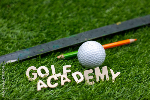 Golf Academy word with golf ball and pencil on green grass photo