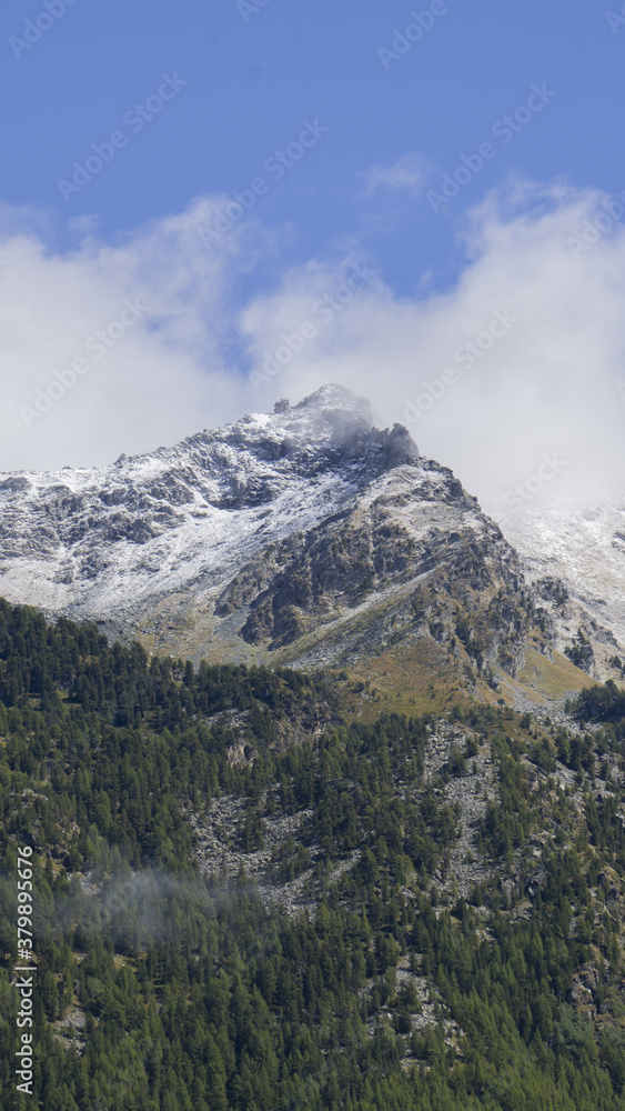Titolo: View of Corno Bussola (Valle d'Ayas, AO) surrounded by clouds and covered by snow after a storm in august.