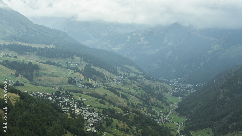 View from above of the Ayas Valley and Champoluc on a foggy day (Aosta Valley) with Antignod village in close-up View from above of the Ayas Valley and Champoluc on a foggy day (Aosta Valley) with Antignod village in close-up