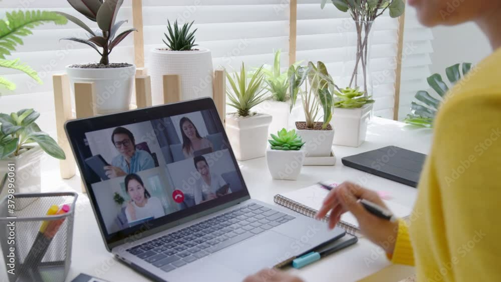 Back view of business woman talking about sale report in video conference. Asian team using laptop and tablet online meeting in video call. Working remotely green home office and Social isolation. Back view of business woman talking about sale report in video conference. Asian team using laptop and tablet online meeting in video call. Working remotely green home office and Social isolation.