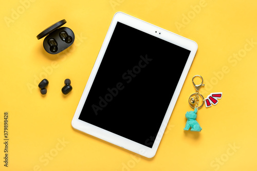 Tablet with black screen and wireless headphones, charger capsule on yellow background Mock up Flat lay Top view Social media, digital marketing concept photo