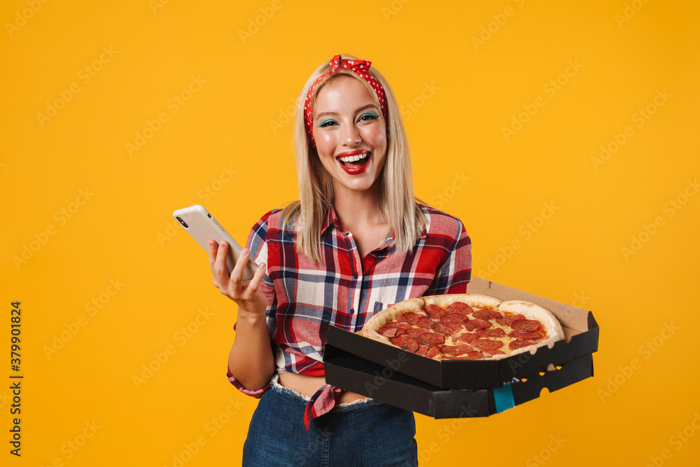 Image of joyful charming pinup girl using cellphone while holding pizza Image of joyful charming pinup girl using cellphone while holding pizza