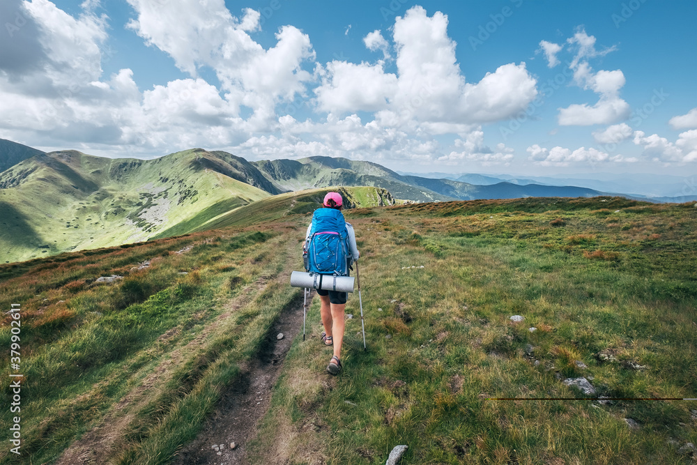 Young hiker woman using a tracking poles with backpack walking by the Slovakian Mala Fatra mountain range. Active lifestyle concept image