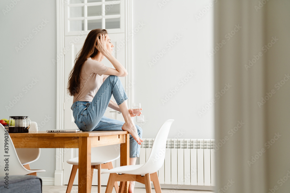 Attractive young woman sitting on a desk at home Attractive young woman sitting on a desk at home