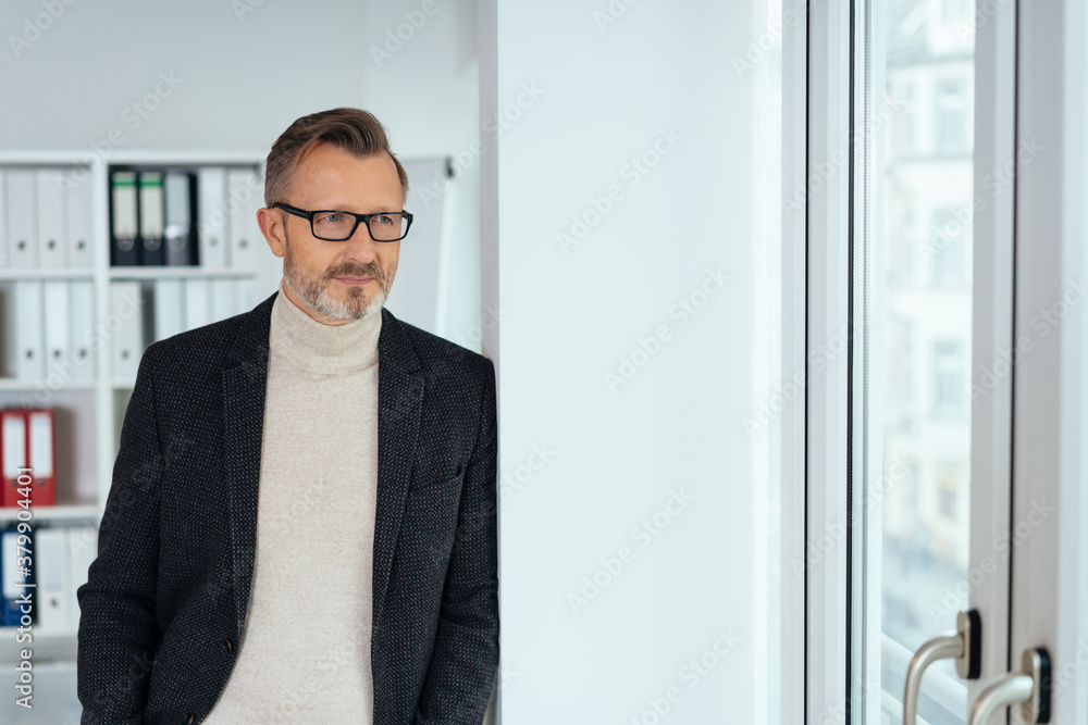 Relaxed businessman looking through a window Relaxed businessman looking through a window