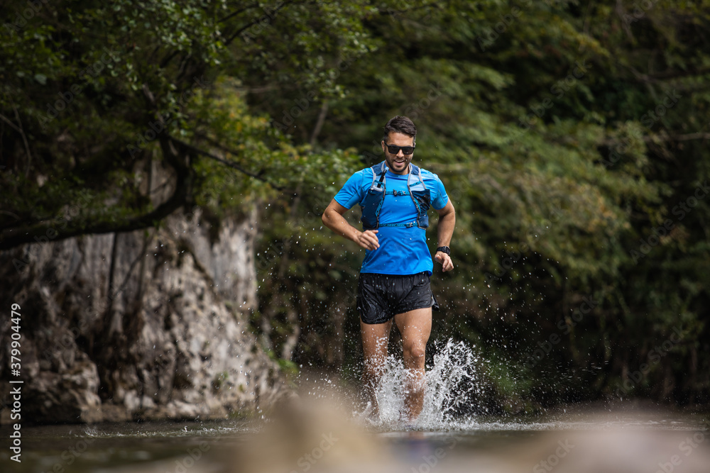 Young man in sports equipment running in mountain river Young man in sports equipment running in mountain river
