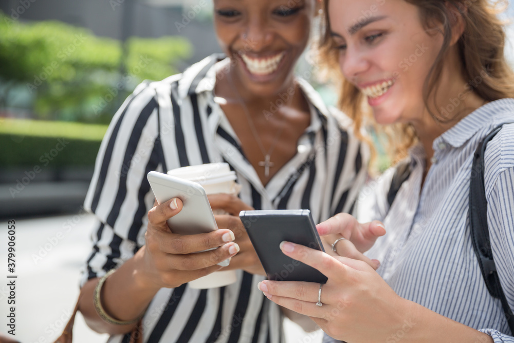 Two beautiful women looking at the smartphone and smiling Two beautiful women looking at the smartphone and smiling