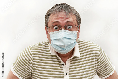 Portrait of a man in medical mask with glasses and bulging eyes. Humor, emotion