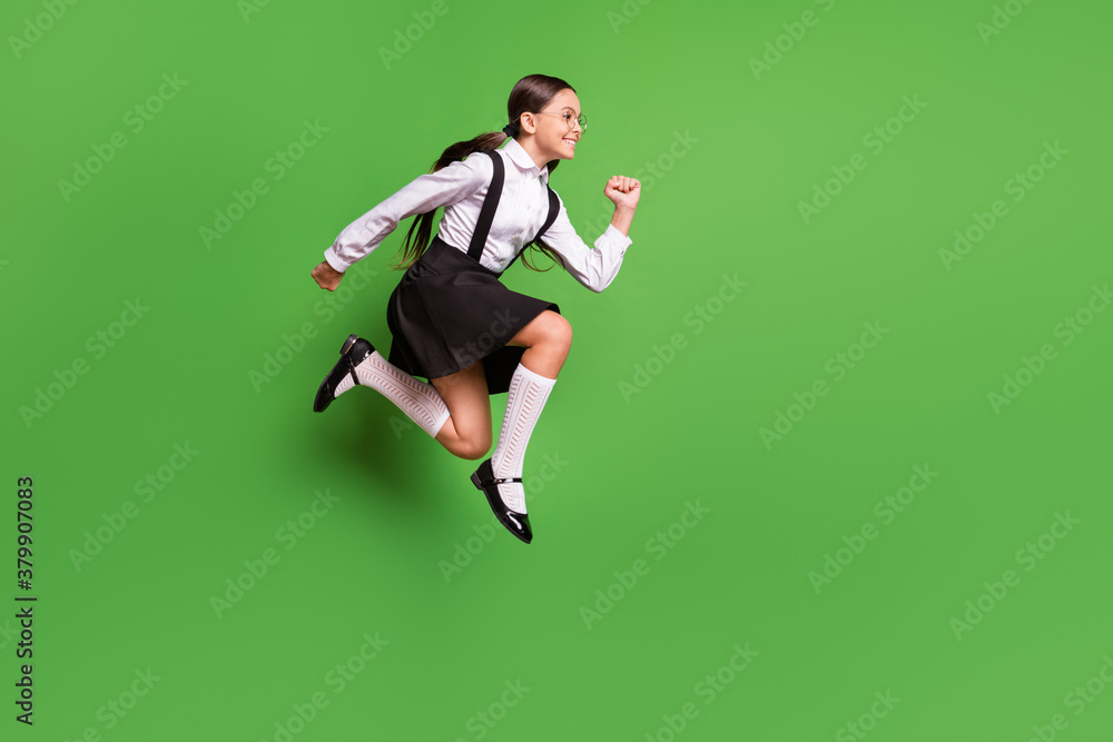 Photo portrait of girl running to school jumping up isolated on vivid green colored background Photo portrait of girl running to school jumping up isolated on vivid green colored background